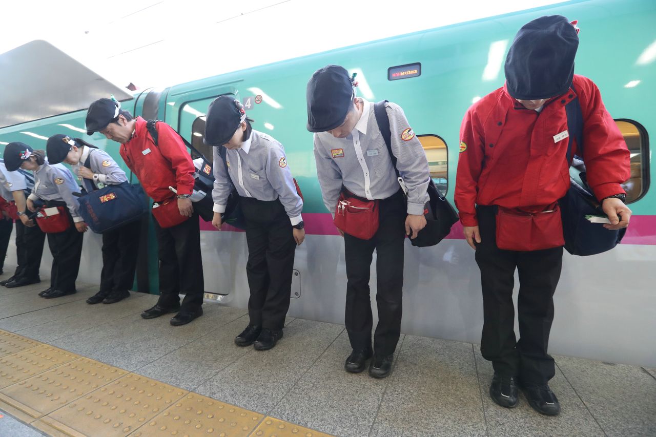 Une équipe de nettoyage des trains à grande vitesse Shinkansen sur un des quais de la gare de Tokyo. Une fois leur travail terminé, les employés ne manquent jamais de s’aligner et de s’incliner pour saluer les voyageurs. (© Jiji Press)