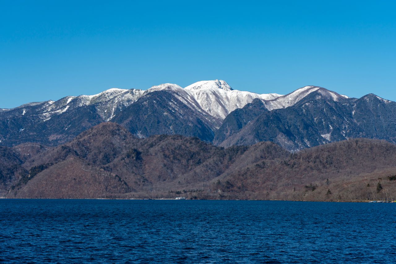 Les sommets enneigés de Nikkô-Shirane, en arrière-plan du lac Chûzenji (© Pixta).