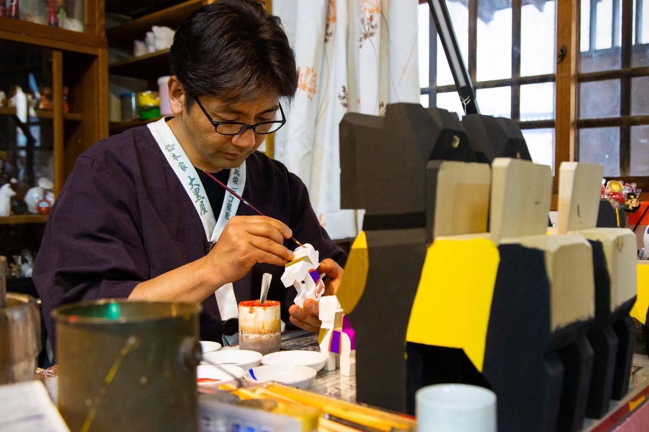 Hashimoto Shôichi dans son atelier, peignant un motif sur une figurine Miharu-goma.
