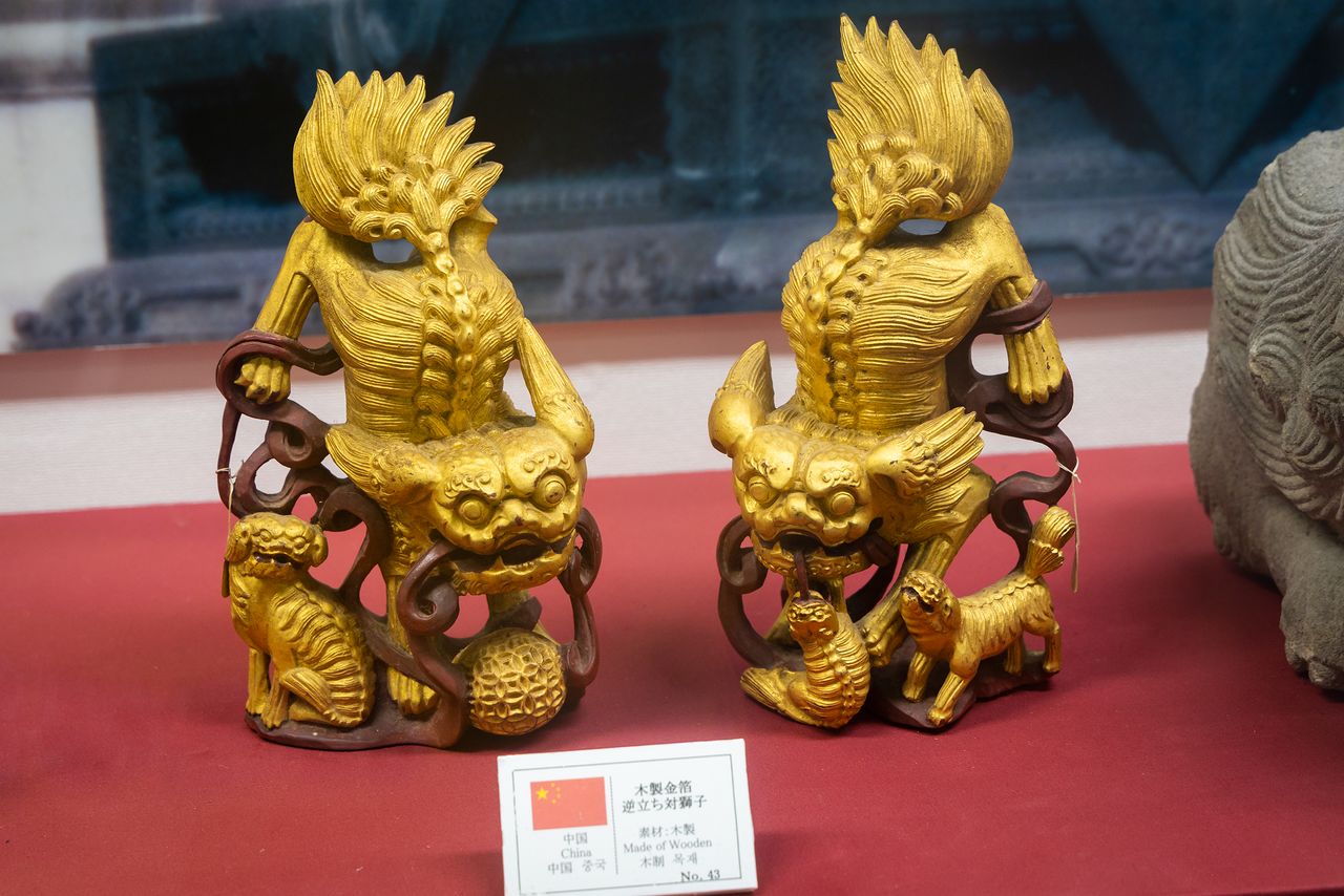 Une paire de lions venus de Chine, tous deux représentés avec la bouche ouverte. La figurine de gauche représente le mâle, caractérisé par le joyau qu’il porte, et la femelle tient son petit à droite. 