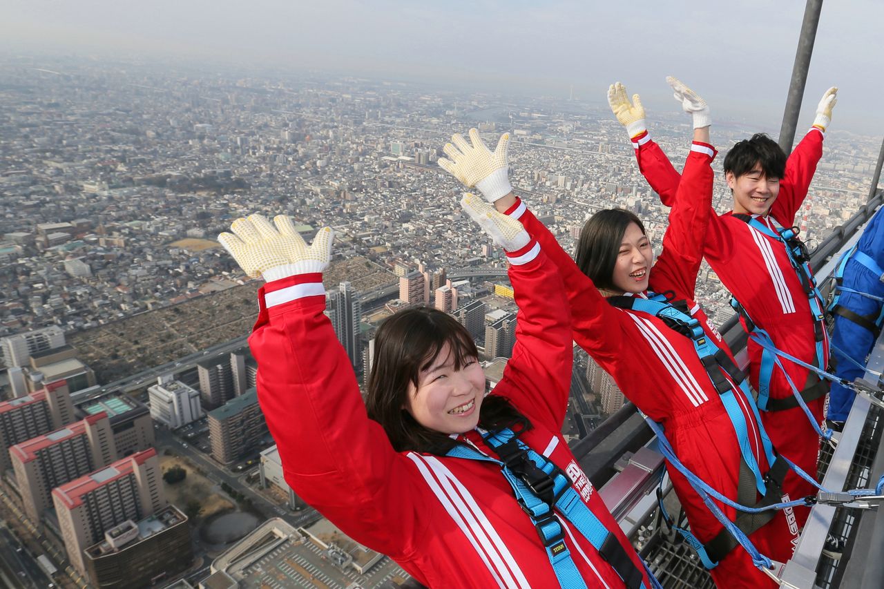 Les visiteurs frissonnent, les cheveux battants au vent, à plus de 300 mètres au-dessus d’Osaka. (© Jiji) 