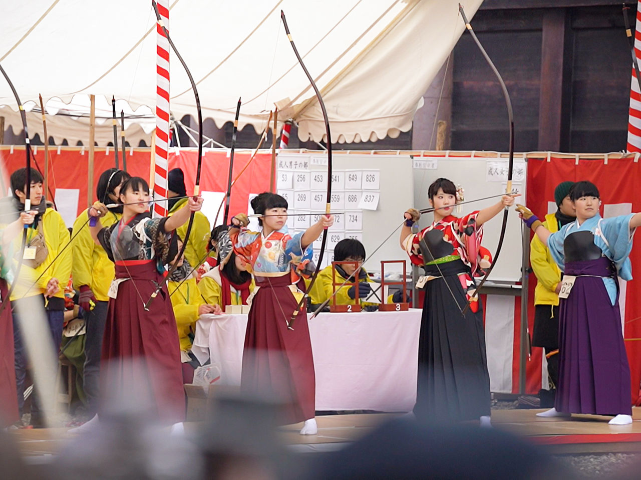 Des jeunes filles, vêtues d’un hakama en forme de jupe-culotte par-dessus leur kimono, tirent à l’arc.