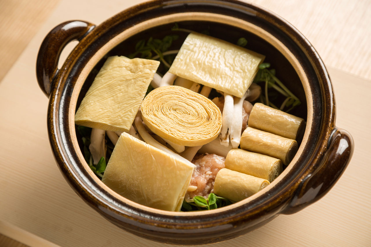 Les ingrédients sont soigneusement disposés uns à uns dans un plat appelé nabé avant de verser le bouillon dashi. De gros morceaux de yuba sont placés sur le dessus. Le tout est lentement mis à mijoter.