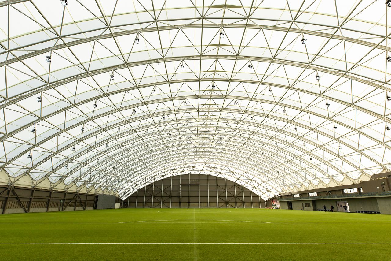 Intérieur du terrain couvert, lumineux même sans éclairage ; la hauteur sous le dôme est adaptée au rugby.