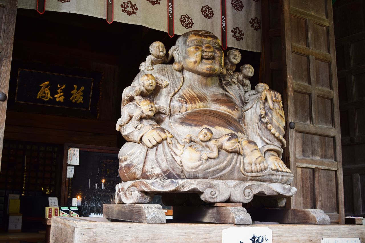 La statue en bois de Hotei, appelé le bouddha rieur, luisante à force d’être touchée par les pèlerins