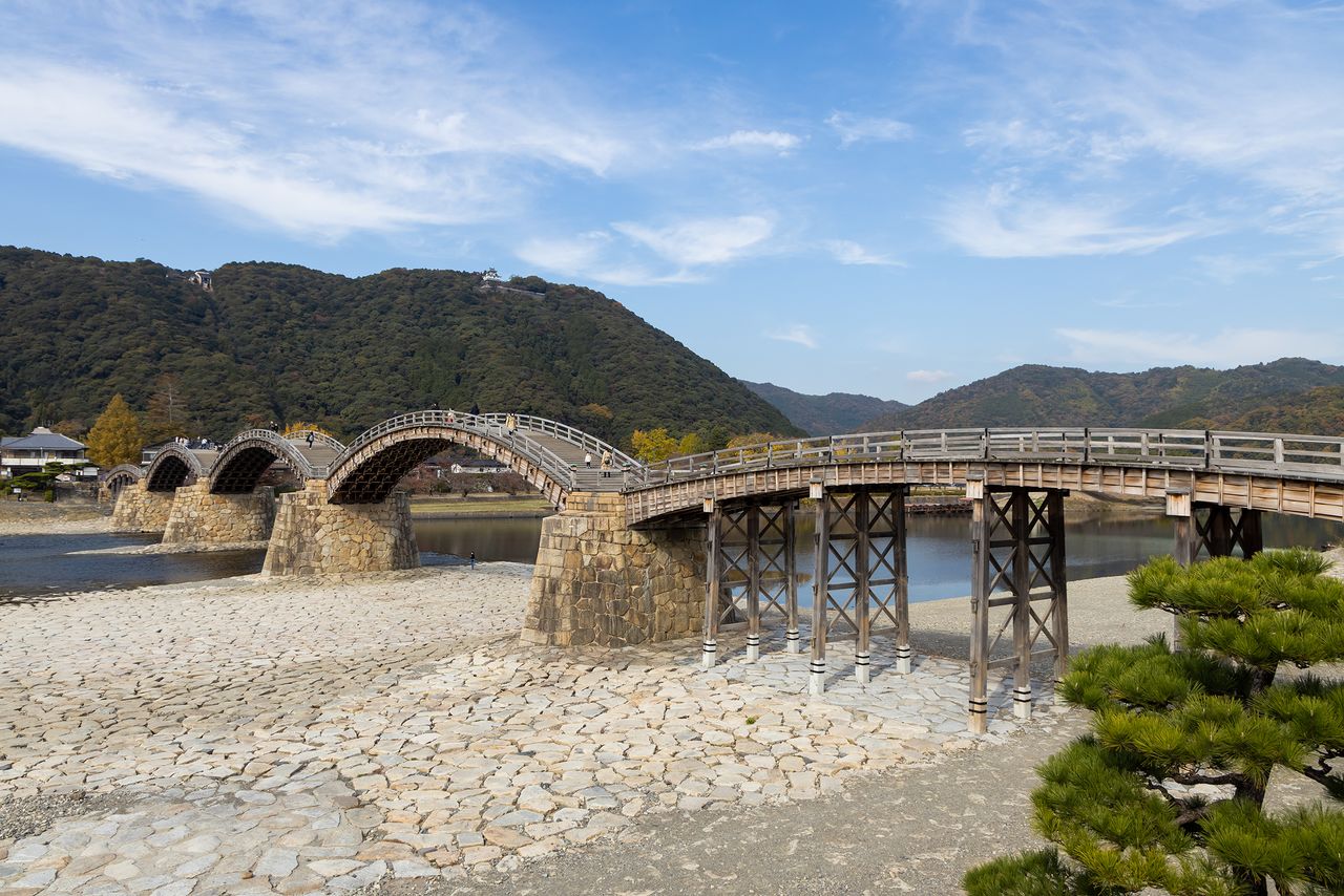 Le pont Kintai, photographié depuis la rive gauche de la rivière Nishiki. On aperçoit le faîte du château d’Iwakuni se détacher en arrière-plan, en haut du promontoire.
