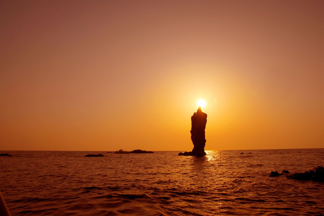 Le coucher du soleil sur le rocher est semblable à une flamme géante qui illumine l’îlot de Rôsoku (« chandelle »). (Avec l’aimable autorisation de la mairie d’Okinoshima)