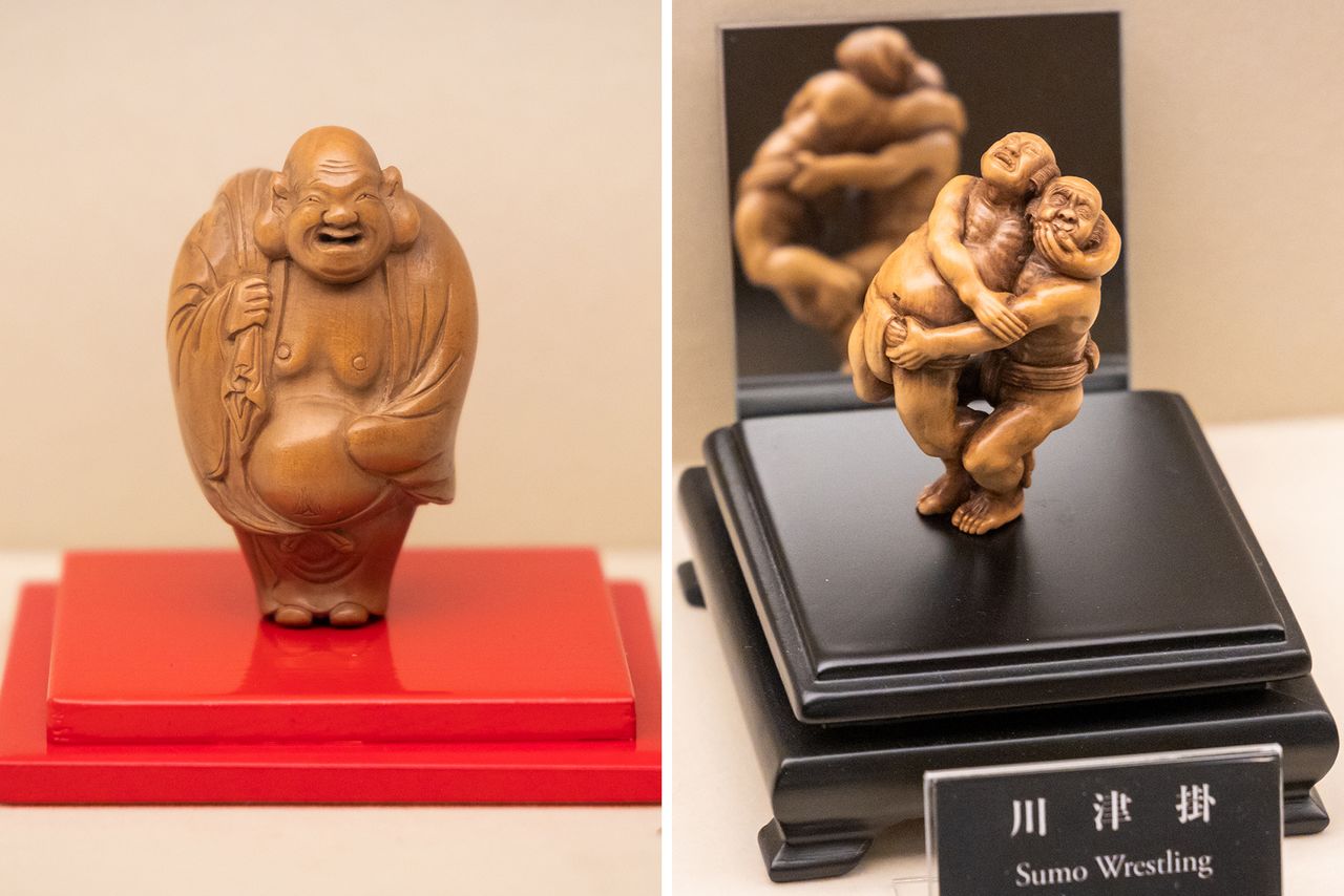 Un grand nombre de netsuke classiques sont exposés, tels que la représentation de Hotei (à gauche), l'une des sept divinités du bonheur. À droite, on voit une œuvre contemporaine, elle aussi en bois, représentant des lutteurs de sumô.