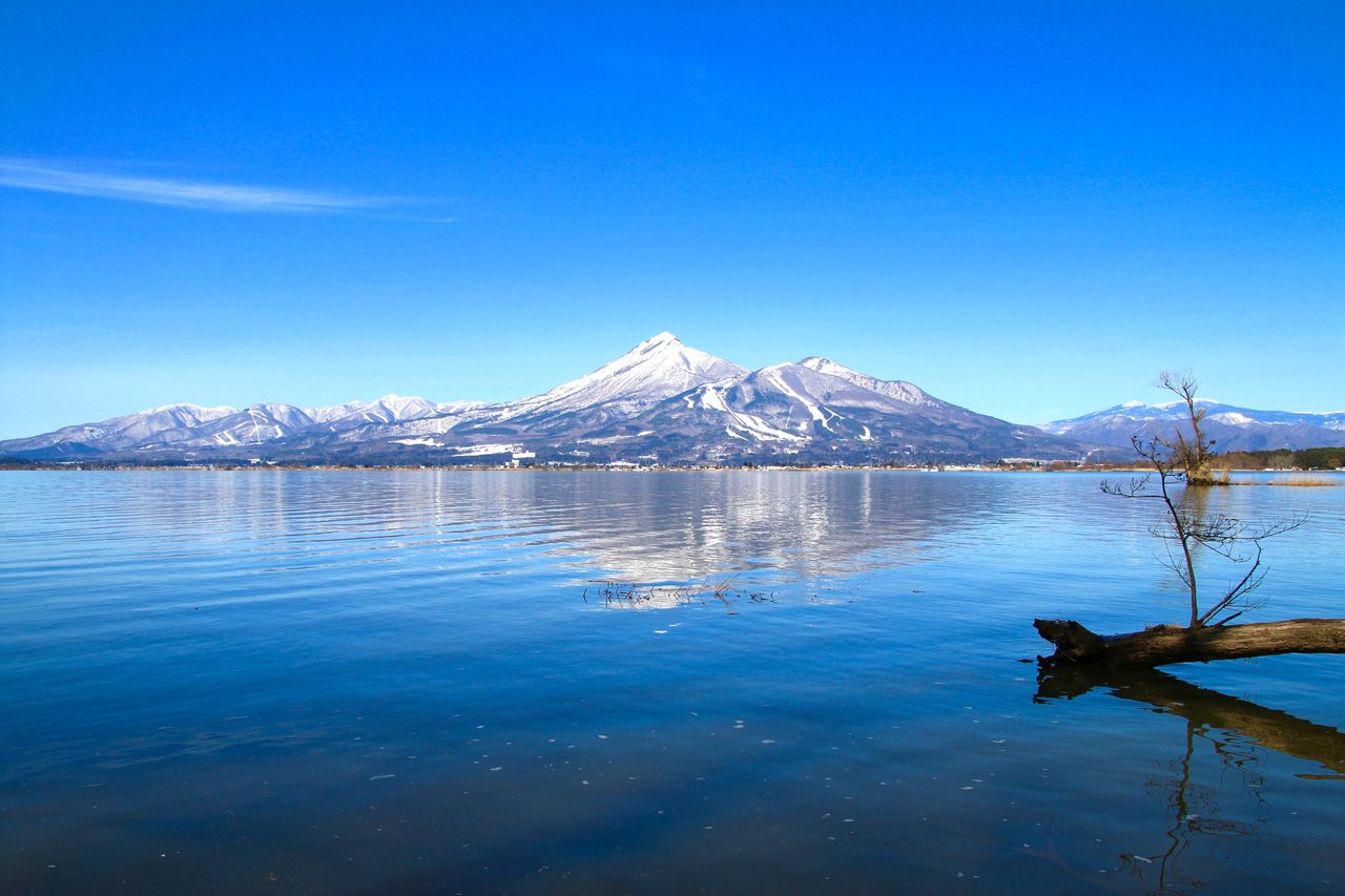 Le mont Bandai se reflète dans les eaux du lac Inawashiro en hiver. (© Pixta)