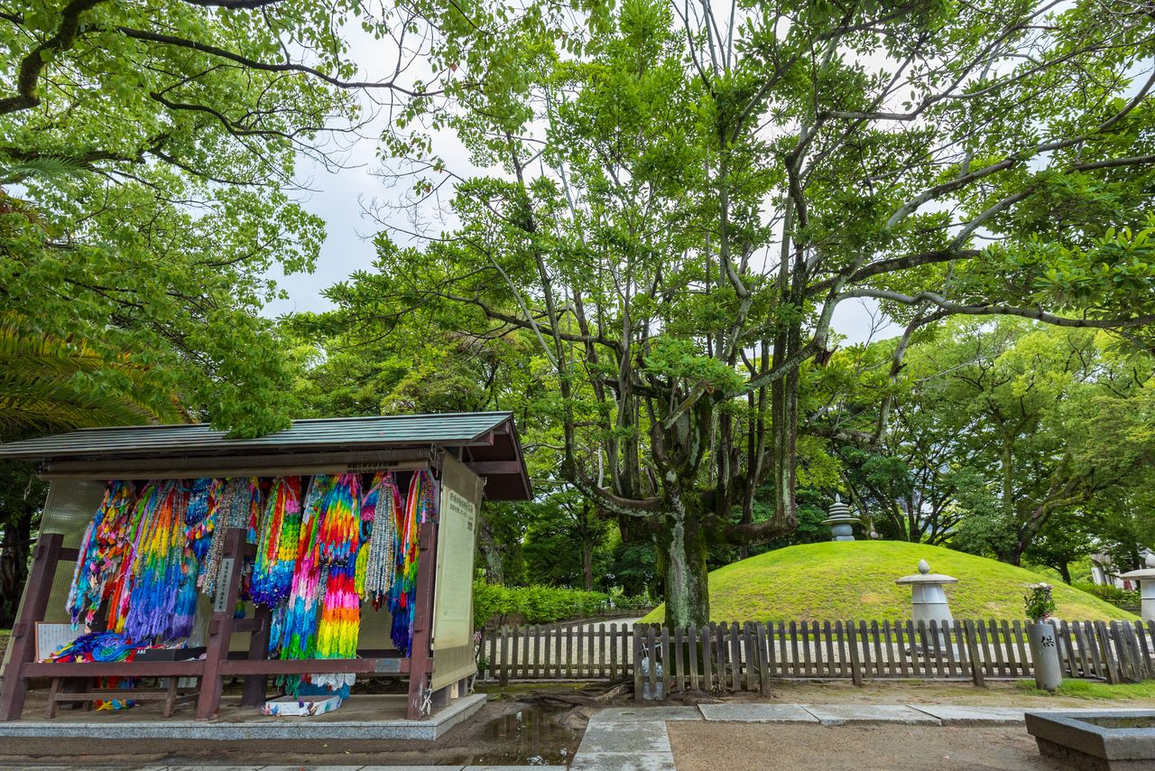 Des origami représentant des grues offertes par des visiteurs sont suspendues devant le tertre funéraire.