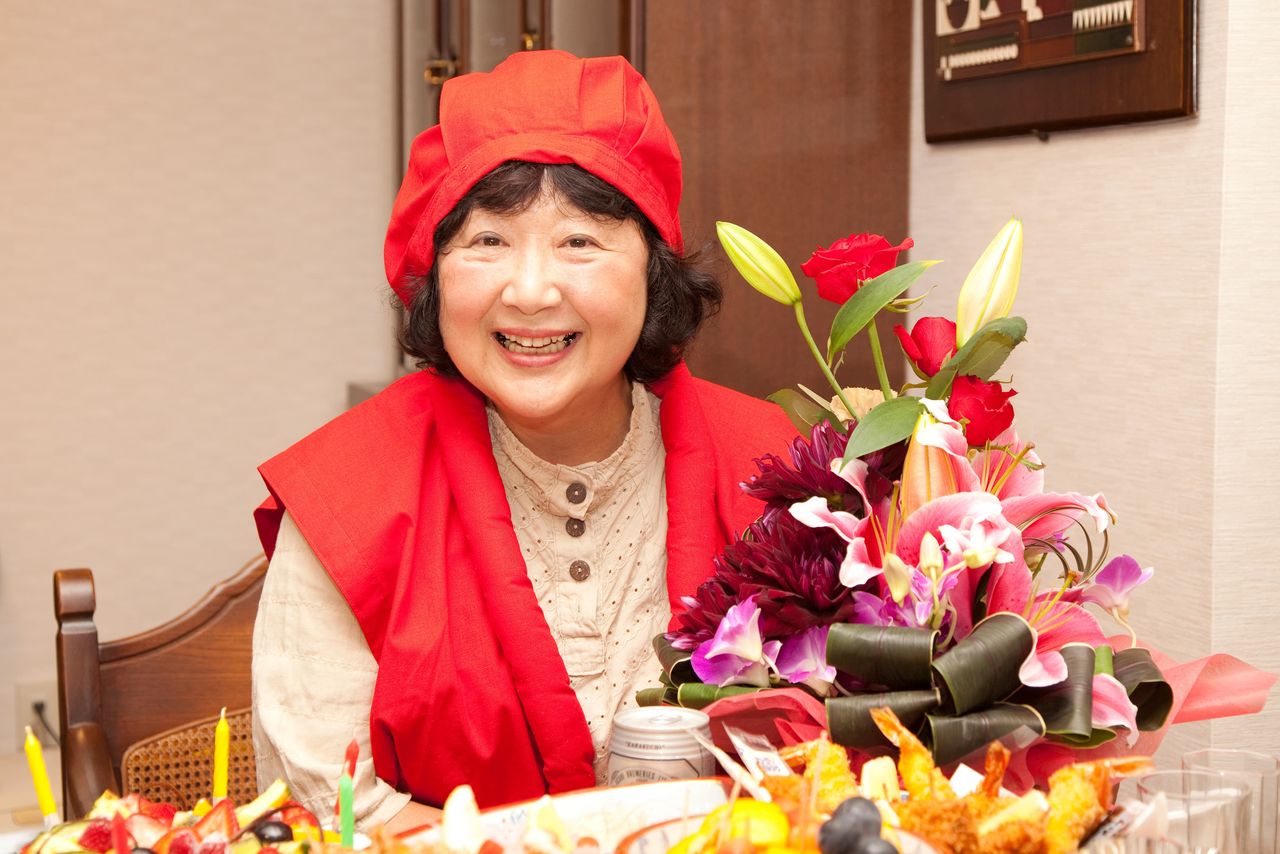 Une Japonaise porte une veste rouge et un chapeau traditionnels pour son soixantième anniversaire. (Pixta)