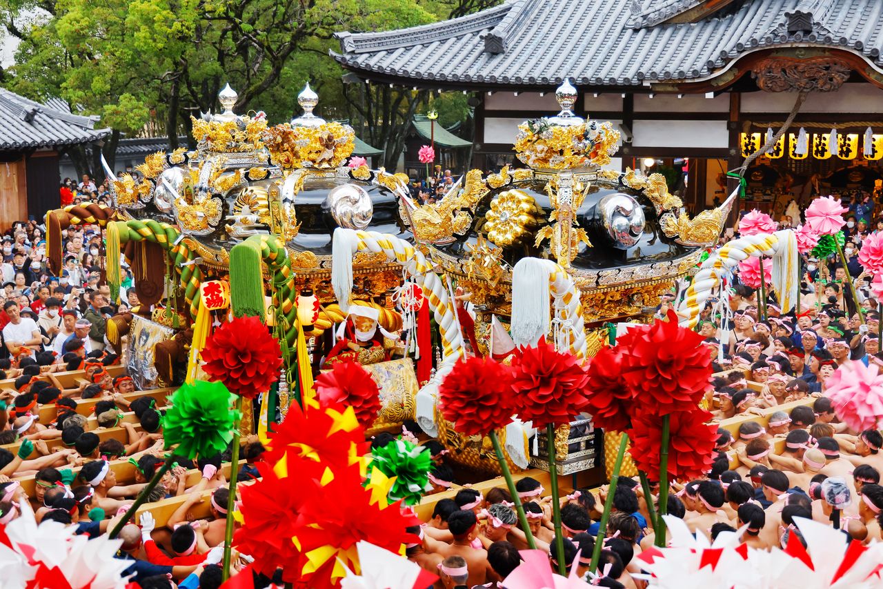 Trois mikoshi richement décorés défilent devant le sanctuaire, portés par les fidèles de sept quartiers, chacun portant un bandeau aux couleurs de son quartier.
