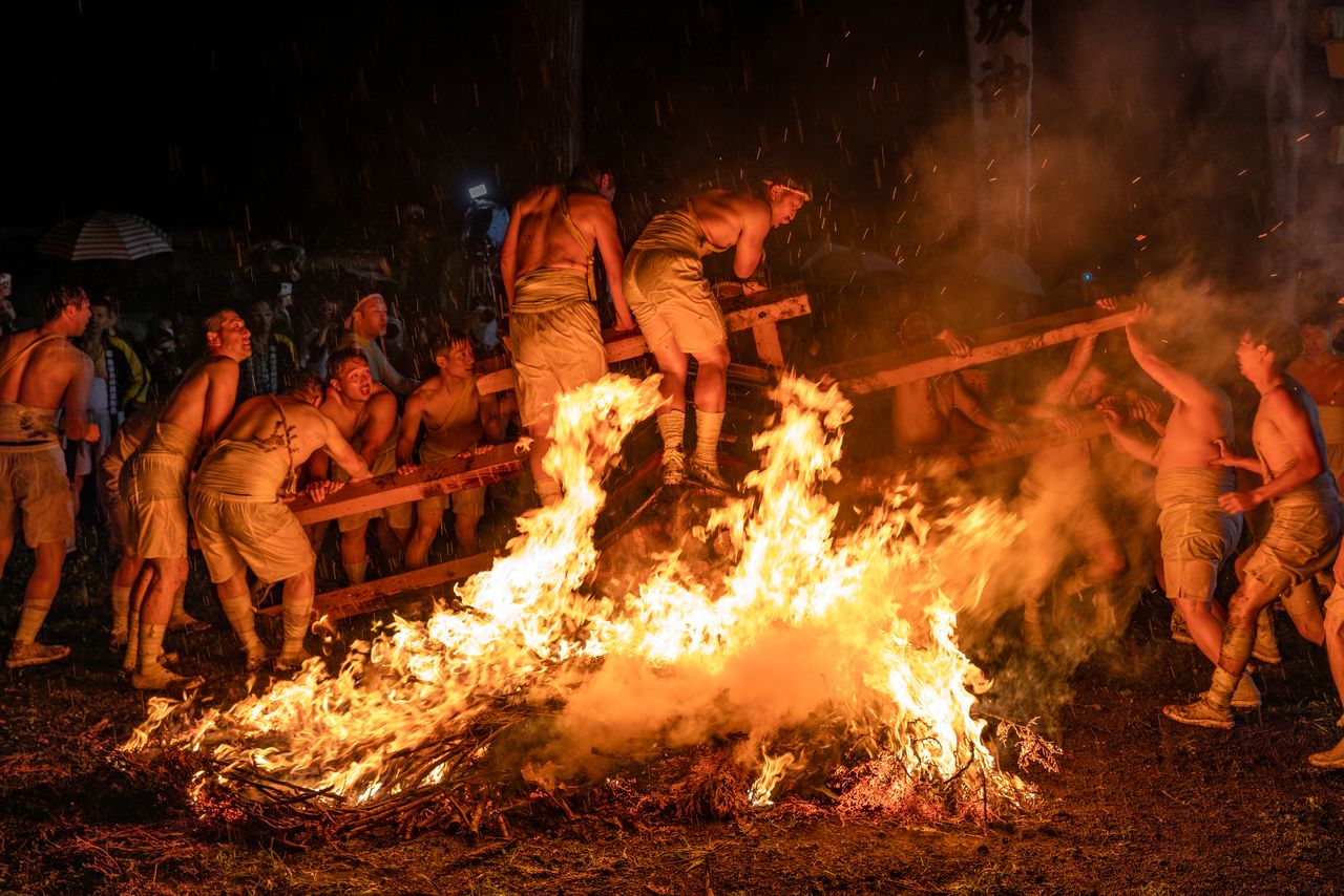Affrontant la chaleur, les porteurs plongent les mikoshi dans le feu. (© Haga Library)