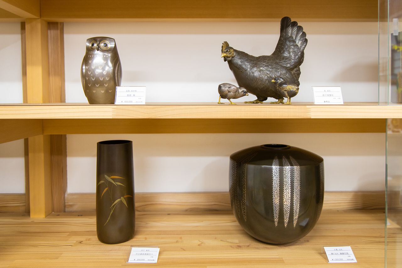 En haut à gauche, une chouette en argent et en bronze avec des incrustations en métal précieux fabriqué par Kanamori Eiichi, un artisan élu « Trésor national vivant ». En bas à droite, un vase en cuivre moulé par Ôzawa Kômin, également « Trésor national vivant ».