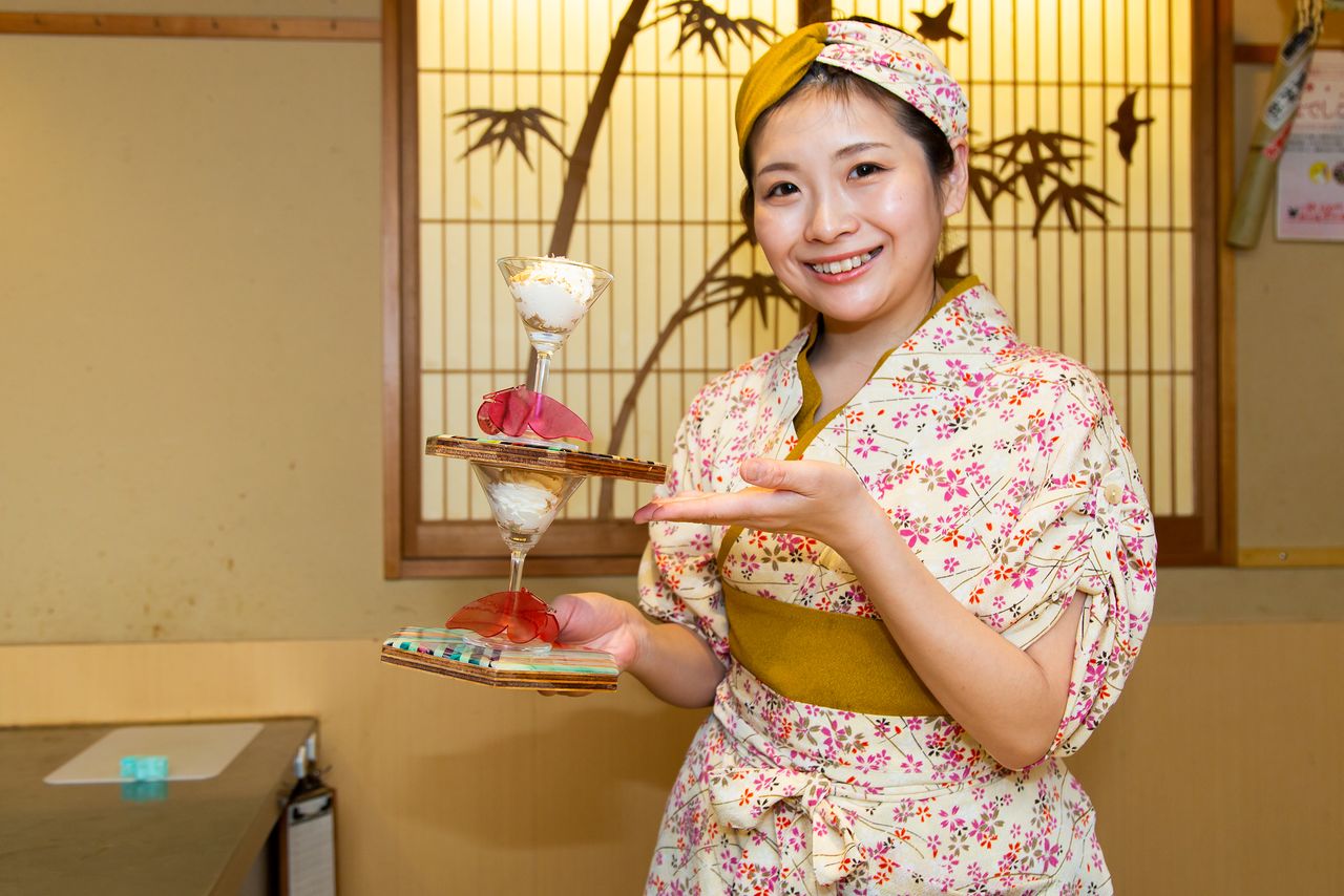 Le restaurant Nadeshico Sushi de Tsukiji, à Tokyo, est dirigé par Chizui Yuki, une des rares femmes maître sushi du Japon. Elle pose en souriant devant l’objectif avec deux coupes de mousse à la daurade rose hakuju madai. Un dessert haut de gamme de son invention.
