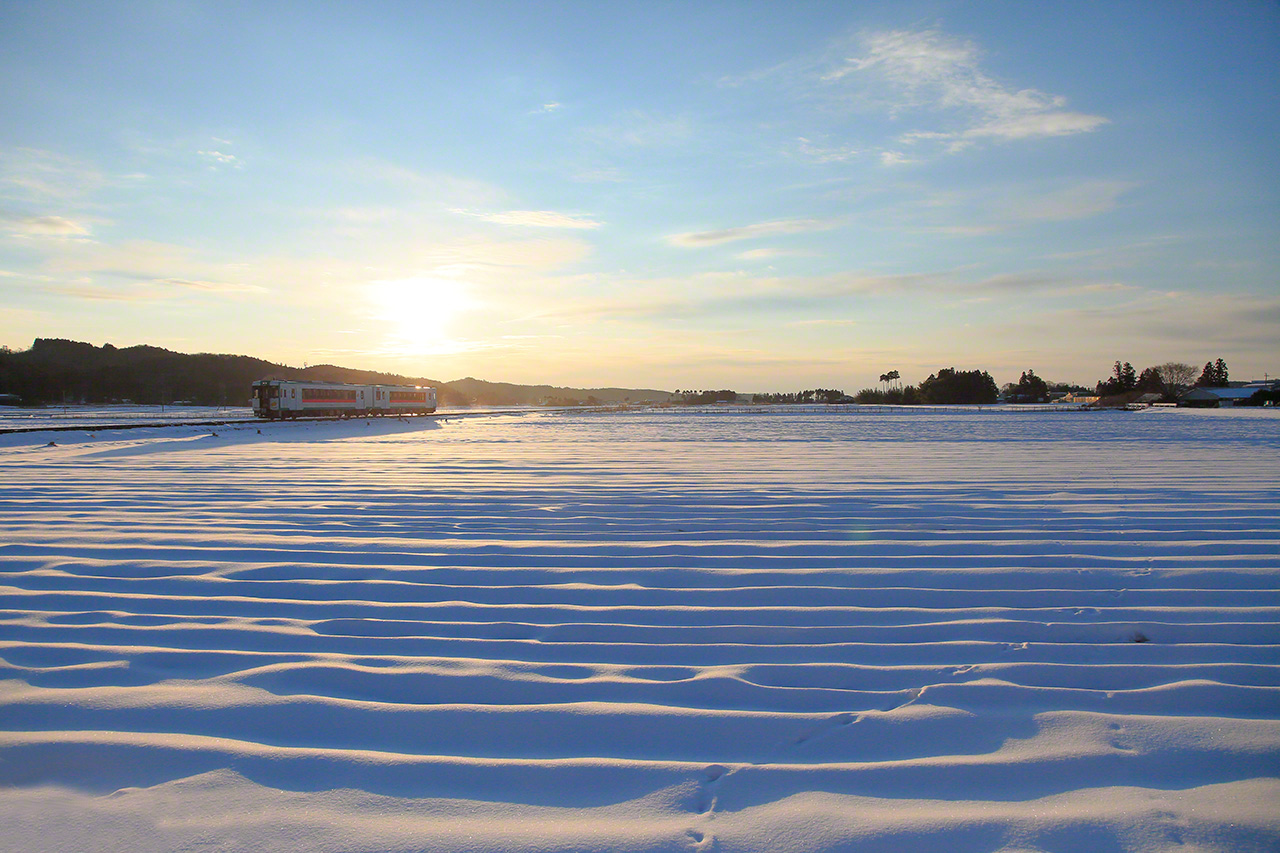 Janvier. Un train diesel de la s&eacute;rie KiHa 110, sur la ligne JR Rikut&ocirc;, entre les gares de Kaminome et Ikezuki, &agrave; &Ocirc;saki, pr&eacute;fecture de Miyagi. Juste apr&egrave;s le lever du soleil, la lueur est presque magique. Pour faire cette photo &agrave; l&rsquo;aube, il m&rsquo;a fallu dormir dans ma voiture. Je buvais mon caf&eacute; quand le premier train de la journ&eacute;e est pass&eacute;.