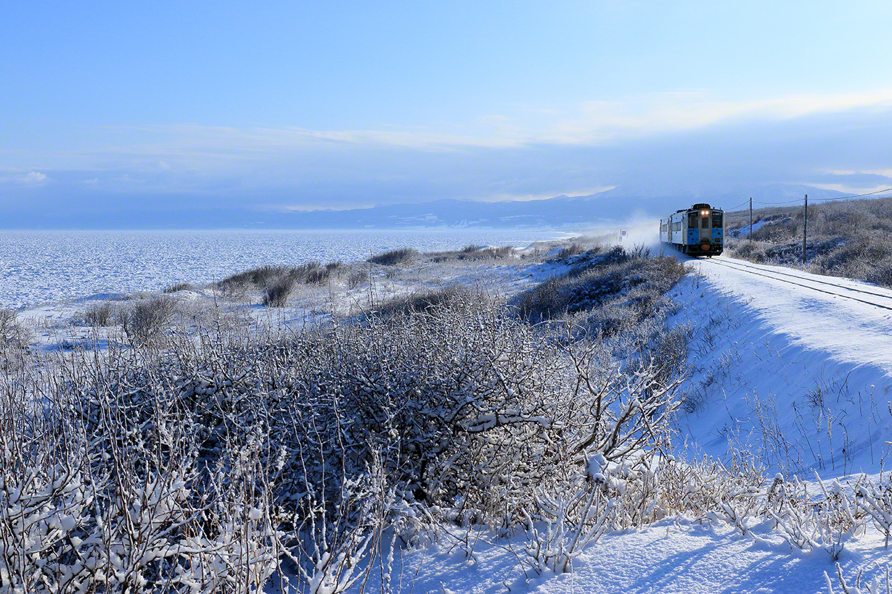 F&eacute;vrier. Un train diesel de la s&eacute;rie KiHa 54, sur la ligne JR Kushiro, entre les gares de Yanbetsu et Shiretokoshari, &agrave; Shari, Hokkaid&ocirc;. Avant de prendre les photos, j&rsquo;ai regard&eacute; si la glace d&eacute;rivante de la mer d&rsquo;Okhotsk arrivait jusqu&rsquo;au rivage. Quand c&rsquo;est le cas, il est parfois difficile de voir o&ugrave; s&rsquo;arr&ecirc;te la glace d&eacute;rivante et o&ugrave; commence la plage.