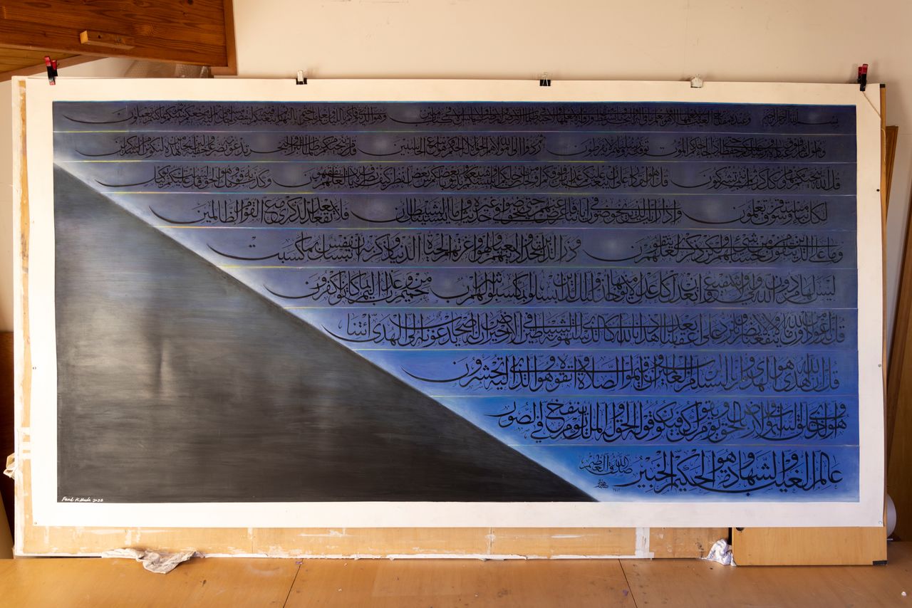 Œuvre représentant un verset du Coran flottant au-dessus d’une dune de sable au soleil du matin.