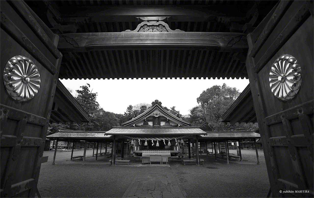 Le pavillon de prière de Hetsu-miya est visible depuis la porte du sanctuaire. À l’arrière de celui-ci se trouve le sanctuaire intérieur, dans lequel la divinité Ichikishima-hime est vénérée. L’emblème impérial, en forme de chrysanthème, est présenté de manière bien visible sur les portes.