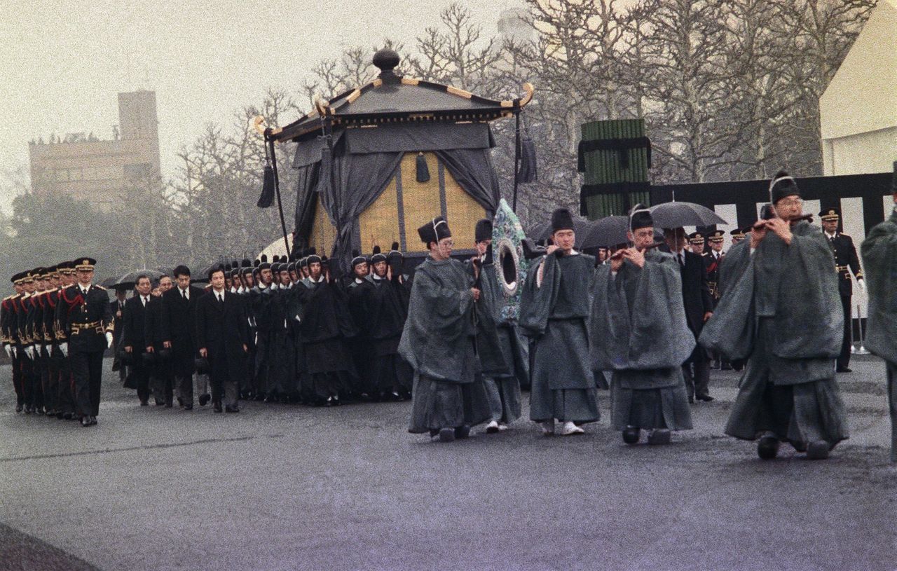 Les membres de la Garde impériale en costume traditionnel portent le palanquin funéraire pour conduire l’empereur Hirohito à sa dernière demeure. (Jiji Press)