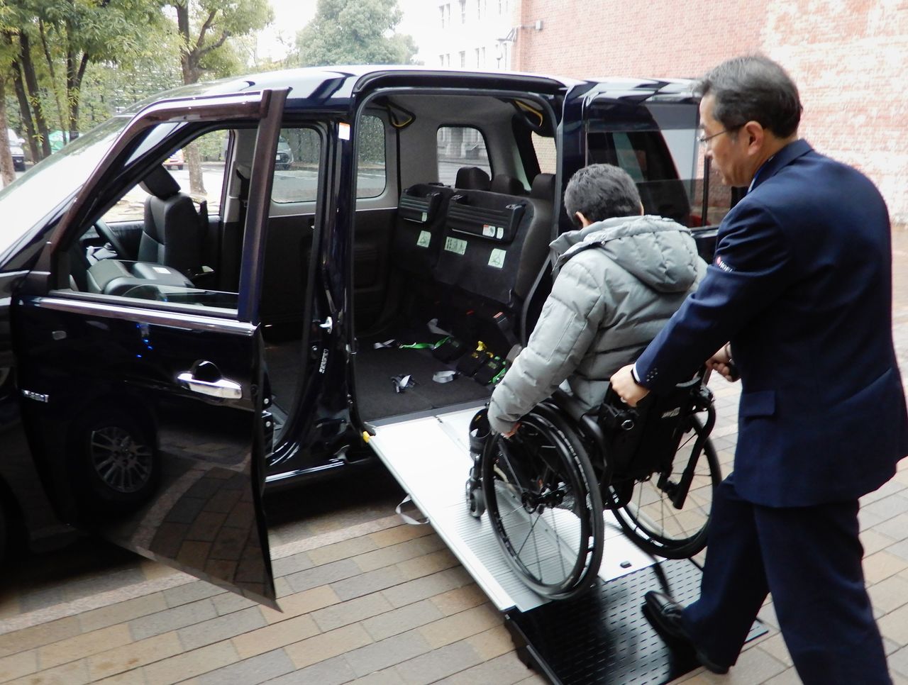 Une personne handicapée en train d’entrer dans la dernière version du Japan Taxi (JPN Taxi), spécialement conçue par le constructeur automobile Toyota pour pouvoir accueillir un passager en fauteuil roulant à l’aide d’une rampe d’accès intégrée. (Photo : Jiji Press)