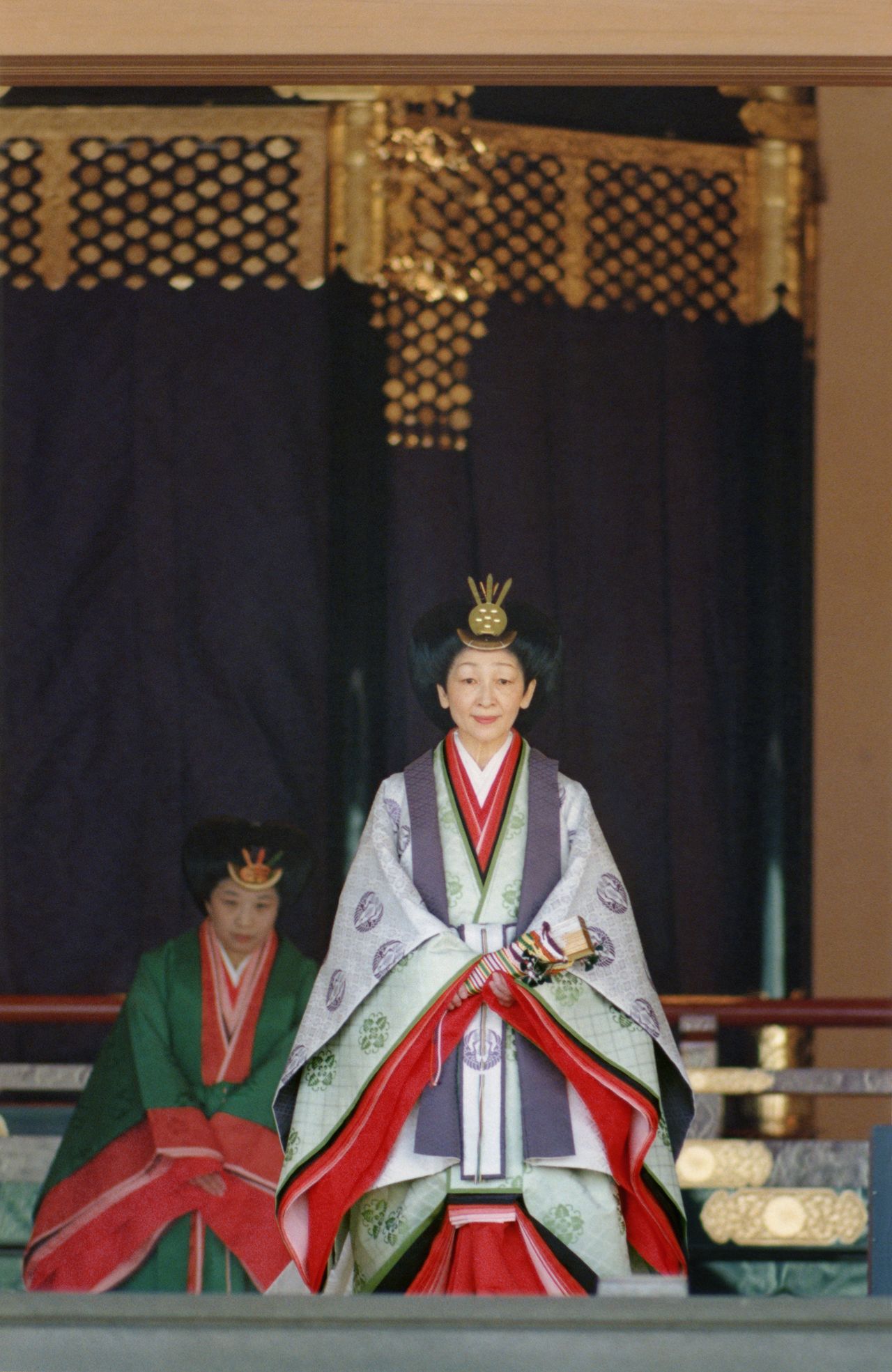L’impératrice Michiko, dans la Salle des Pins du palais impérial. Elle est vêtue du kimono d’apparat <em>jûni-hitoe</em> (formé de cinq couches de damas). Dans sa main, elle tient un éventail de cérémonie appelé <em>hiogi</em>. (12/11/1990. Photo : Jiji)