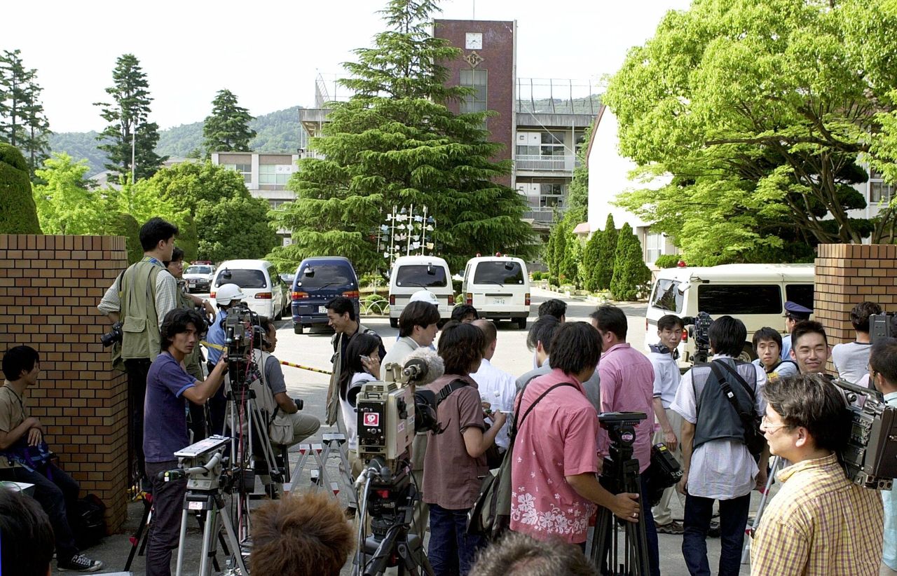 Le 8 juin 2001, les journalistes rassemblés devant l'entrée principale de l'école primaire Ikeda rattachée à l'université d'éducation d'Osaka, où un homme armé d'un couteau s'était introduit et venait de poignarder plusieurs élèves et enseignants, tuant 8 enfants et blessant plus de 20 personnes. (Jiji)