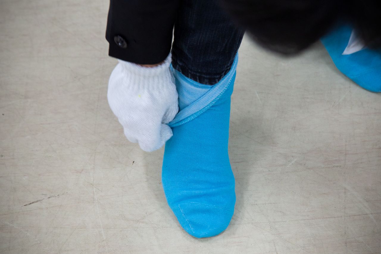 Préparatifs avant de pénétrer sur le site : des gants et deux paires de chaussettes superposées ; le bas du pantalon est glissé dans les chaussettes pour fermer la voie aux poussières