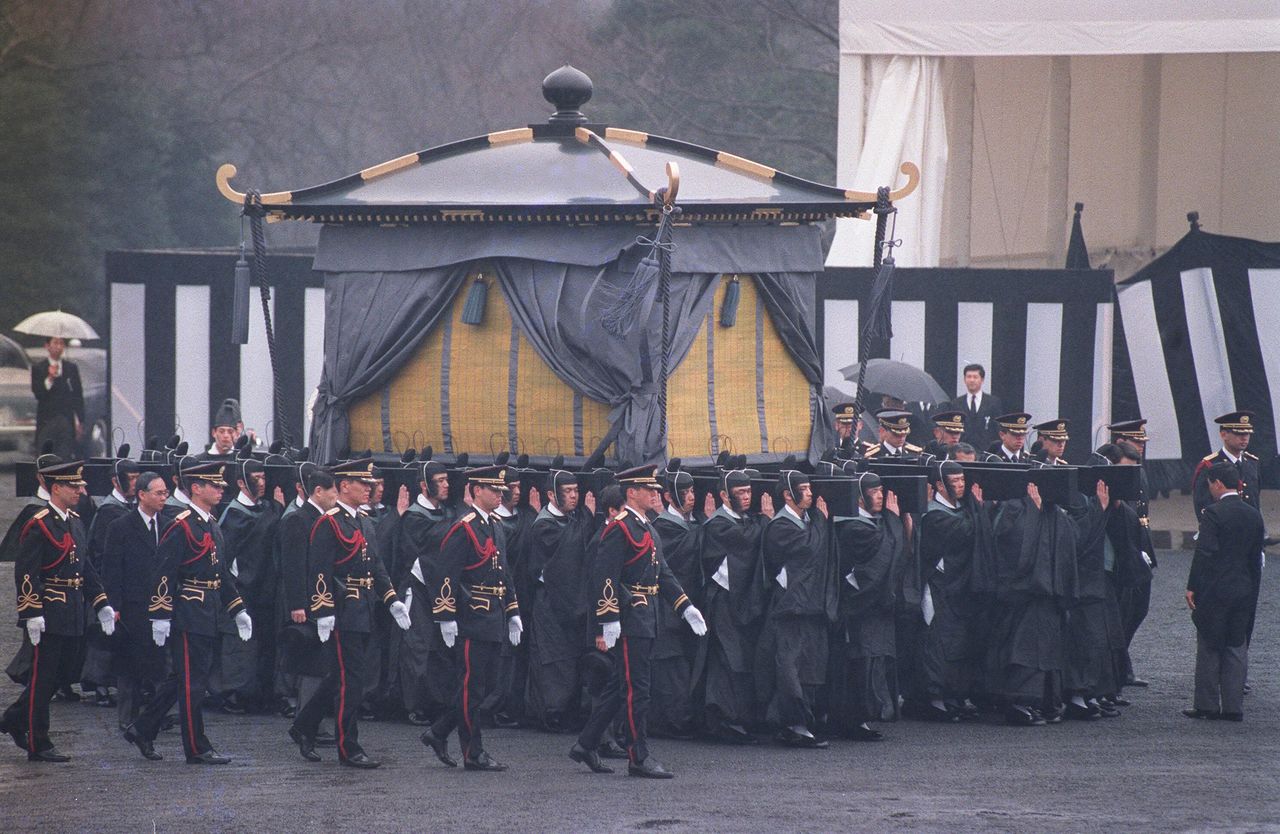Le palanquin funéraire porté par les hommes de la Garde Impériale revêtus d’un habit ancestral. Le 24 février 1989, dans les jardins impériaux de Shinjuku, à Tokyo. (Jiji Press)
