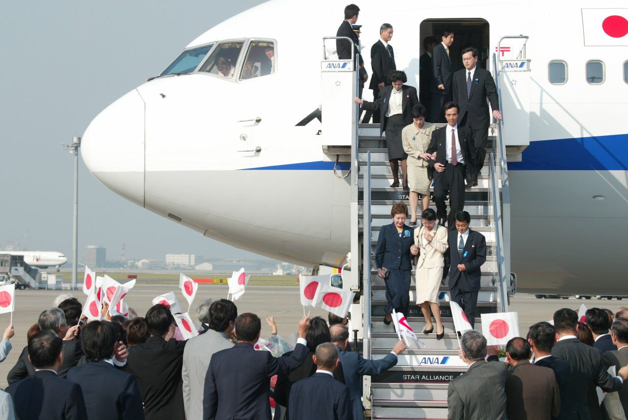 Des victimes des enlèvements descendent la rampe d’un avion affrété par le gouvernement et foulent de nouveau le sol japonais pour la première fois en 24 ans. (Aéroport de Haneda, Tokyo, 15 octobre 2002)