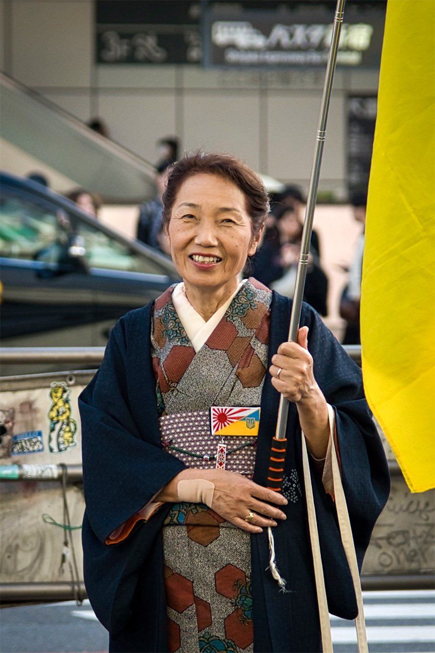 Une femme manifeste son soutien au pays en portant un drapeau ukrainien lors d'une manifestation, en novembre 2024 à Tokyo. (© Yuliana Romaniv)