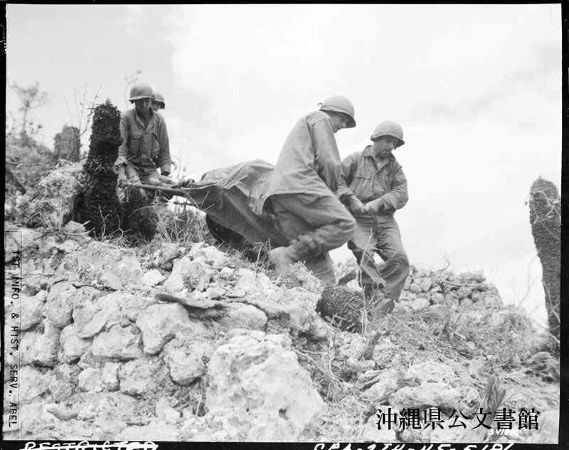 Des soldats américains transportent le corps d’un camarade tombé au combat près des ruines du château d’Urasoe, durant la bataille d’Okinawa, le 22 avril 1945. (Archives préfectorales d’Okinawa)