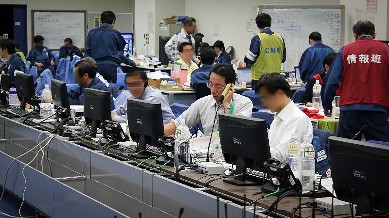 M. Masuda, alors directeur de la centrale, dirigeant les opérations dans la salle de contrôle opérationnelle du bureau d'intervention d'urgence de Fukushima n° 2, aux commandes (Avec l'aimable autorisation de TEPCO HD.) Image partiellement modifiée.