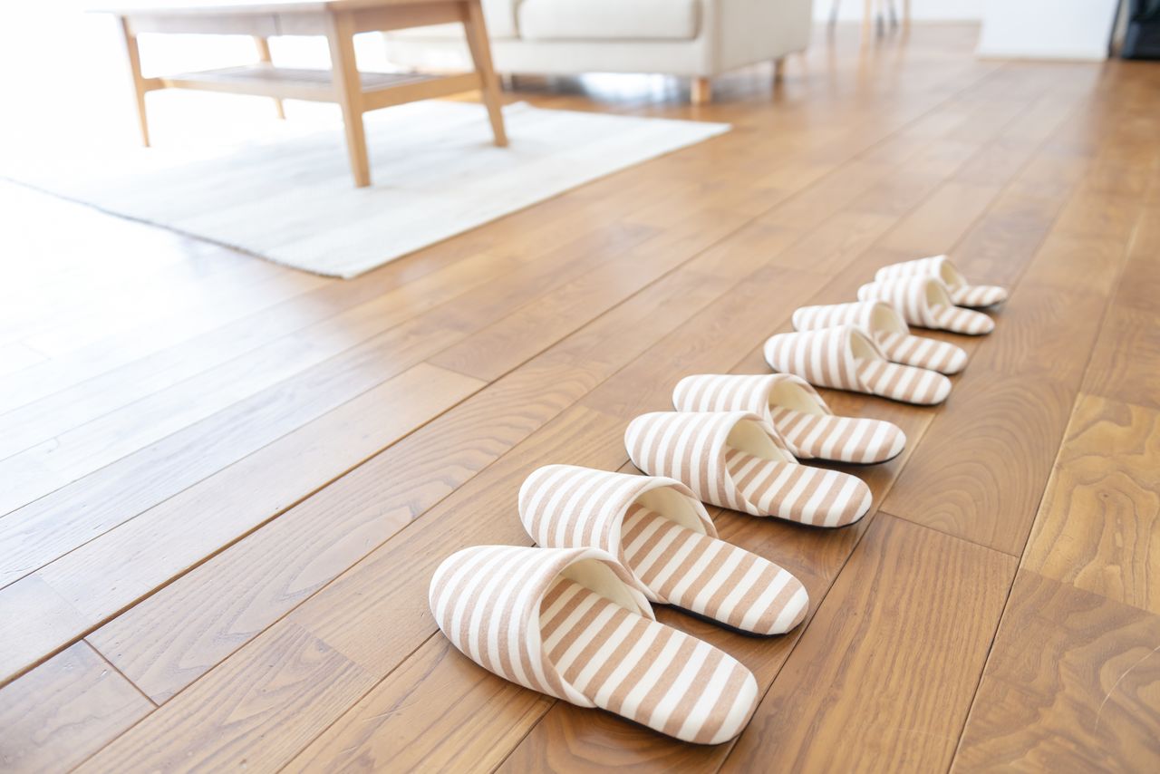  Des chaussons d’intérieur à rayures prêts à l’usage, dans un logement japonais contemporain équipé de planchers et de meubles de style occidental (Pixta)