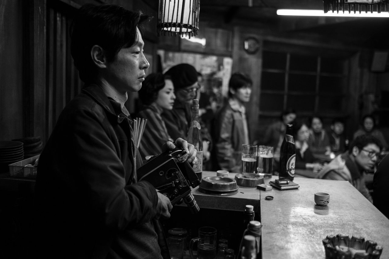 Une scène dans une taverne où se réunissent des pêcheurs. Au premier plan, Kase Ryô joue le rôle de Kiyoshi, un membre clé des « négociateurs individuels » ©2020 MINAMATA FILM, LLC ©Larry Horricks