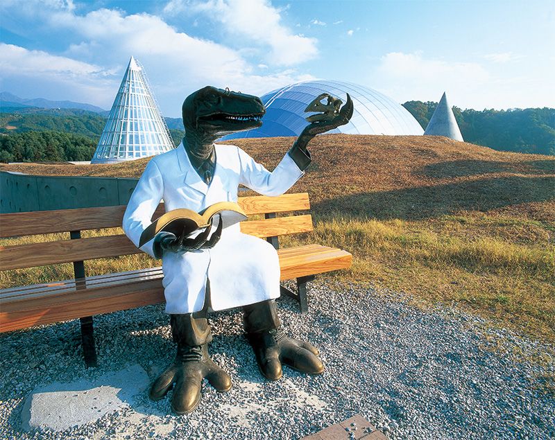 En dehors du musée, le Dr. Dinosaure attend patiemment que les visiteurs prennent des photos commémoratives avec lui.