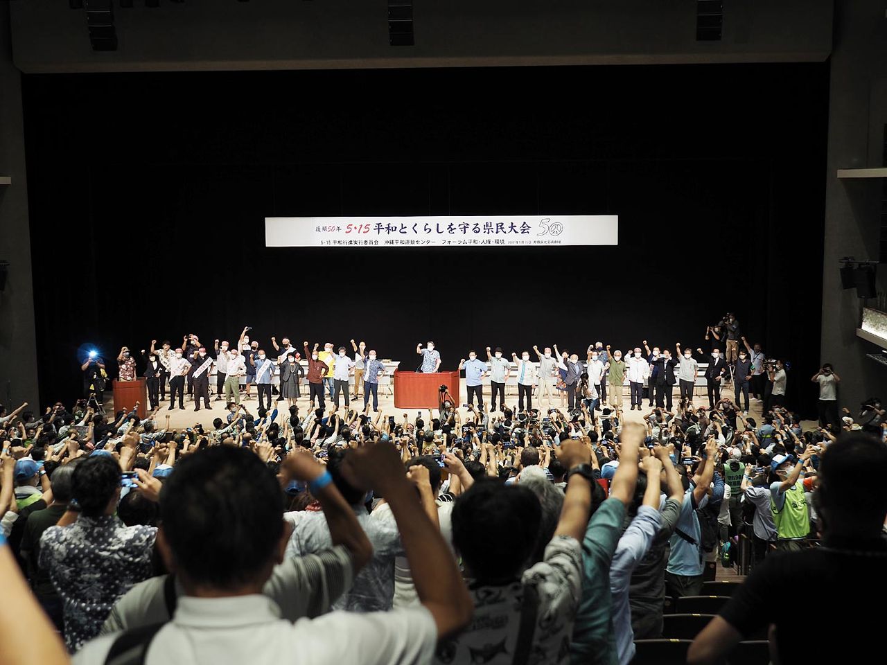 Les participants du meeting préfectoral “15 mai, Les Okinawaïens pour la Vie et la Paix” lèvent le poing pour demander la réduction des bases militaires américaines à Okinawa.