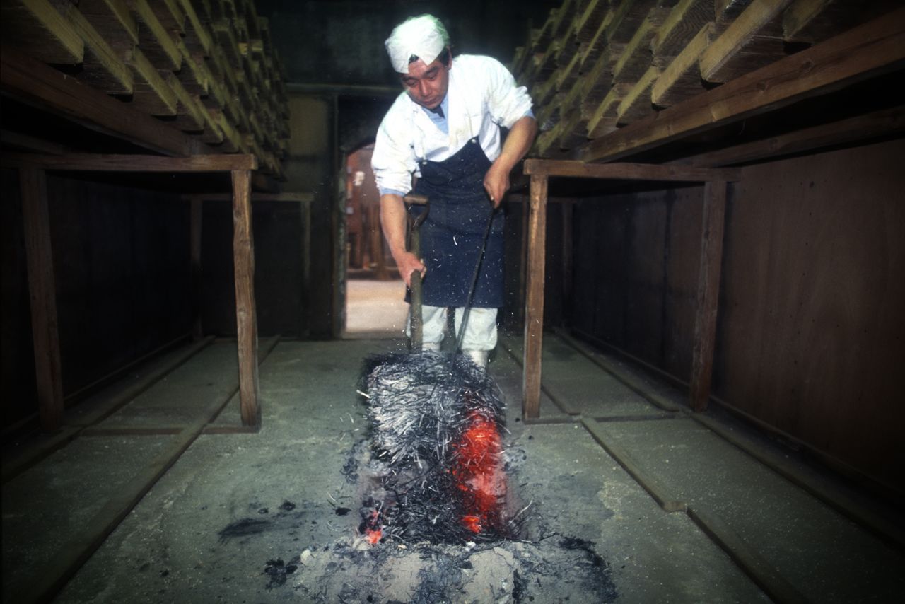 Un travailleur couvre les braises incandescentes de cendres de paille afin de chauffer le kôji-muro. 