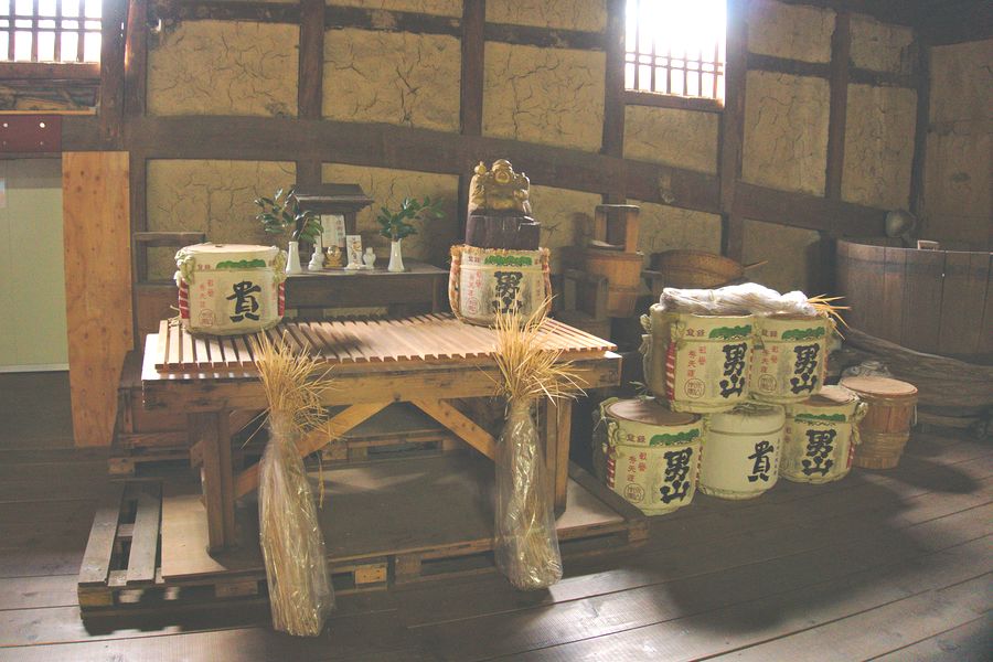 Des fûts de saké avec des gerbes de riz récolté localement sont placés devant l'autel de la brasserie. 