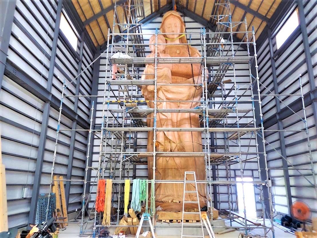 La statue a été transportée en plusieurs pièces depuis le studio Fujisawa, atelier de l’artiste, jusqu’à l’enceinte qui lui est dédiée, où elle a été ré-assemblée. La Vierge Marie n’attend plus que d’être peinte.