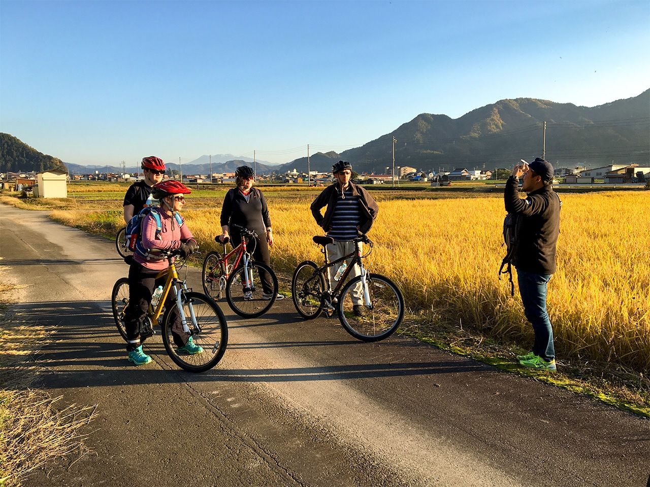 Les cyclistes s’arrêtent le long du chemin pour écouter les explications de l’accompagnateur.  (© Demachi Yuzuru)