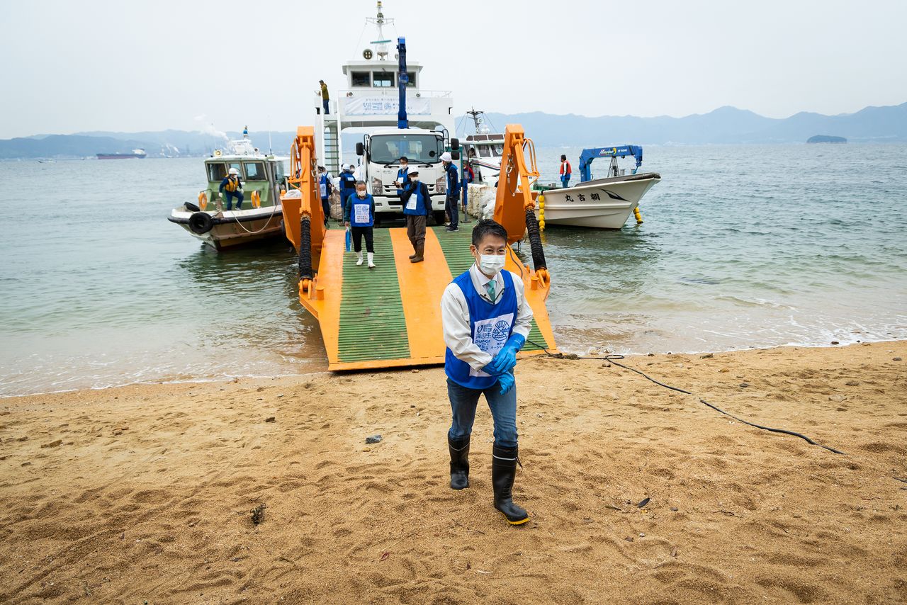 Yuzaki  Hidehiko, gouverneur de la préfecture de Hiroshima, arrive sur la plage par le débarcadère du chaland.