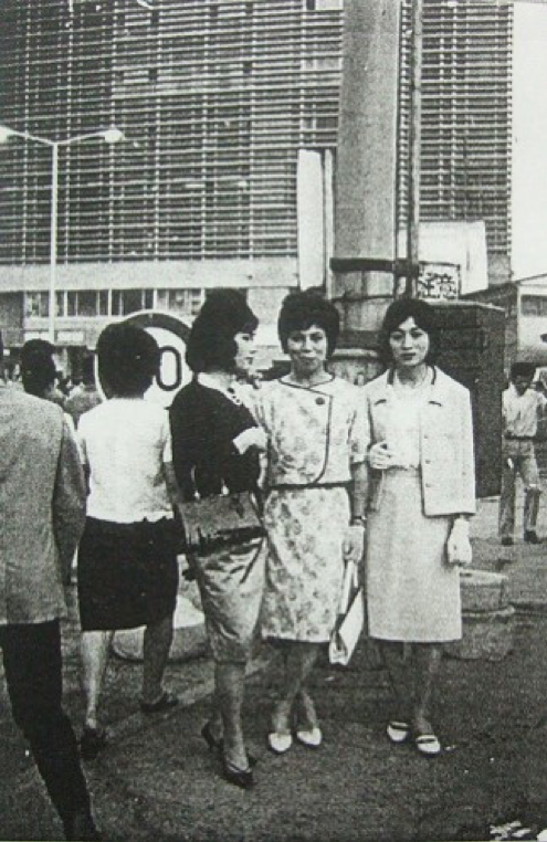 Des membres du club secret de travestissement Fuki, posant pour une photo devant le bâtiment rénové de la gare de Shinjuku, en juin 1964.
