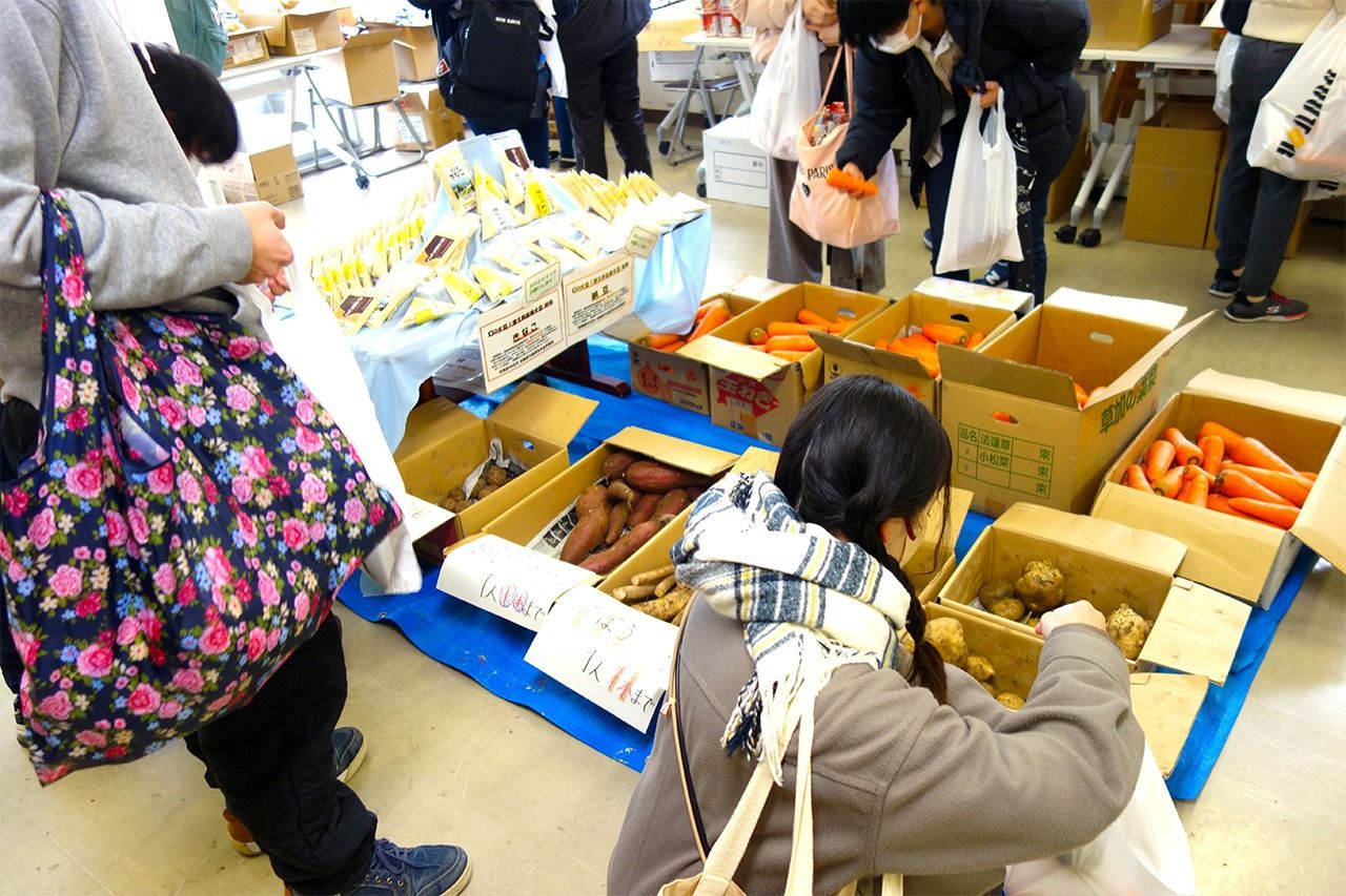 Des participants lors d’un événement organisé pour les étudiants de Sagamihara sillonnent les rayons de légumes et autres produits offerts par les producteurs locaux. (© Nippon.com)