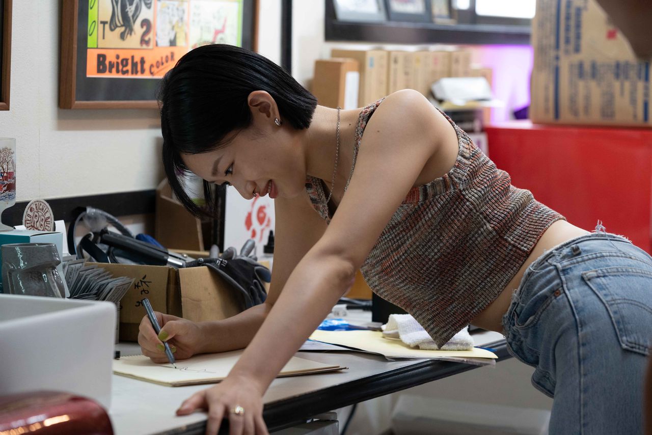 Kana dessine le motif d’un tatouage pour son petit ami. (© 2024 Desert of Namibia Production Committee)