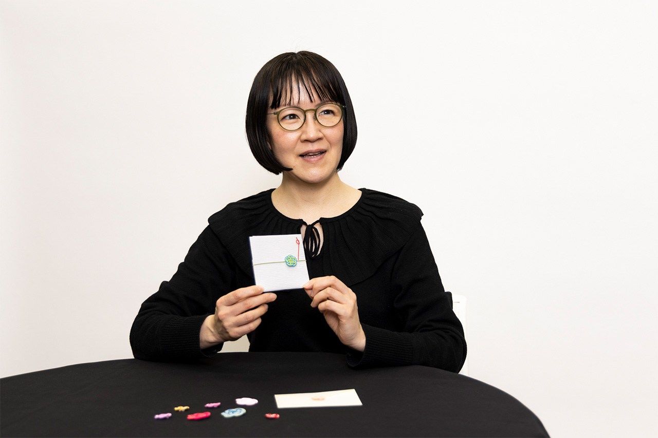 « Intégrer des motifs de toutes les couleurs dans l’art traditionnel du mizuhiki m’a permis de faire le lien avec les jeunes », raconte Morita. « Le simple geste de rajouter un mizuhiki à une enveloppe en dit long sur les sentiments de la personne qui l’offre. » (© Kawamoto Seiya)