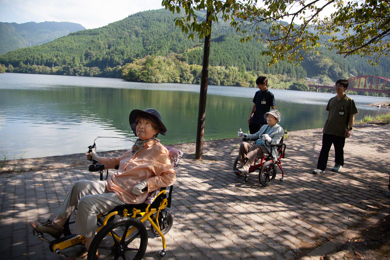 Deux amies, l’une de 94 ans et l’autre de 83 ans, prennent l’air en faisant le tour du lac en COGY. Cela fait six ans qu’elles utilisent les fauteuils à pédales. L’une d’elles raconte :« J’avais tellement mal au genou que je me rendais chez mon médecin deux fois par semaine pour des piqûres. Grâce au COGY, je n’y vais plus du tout ».