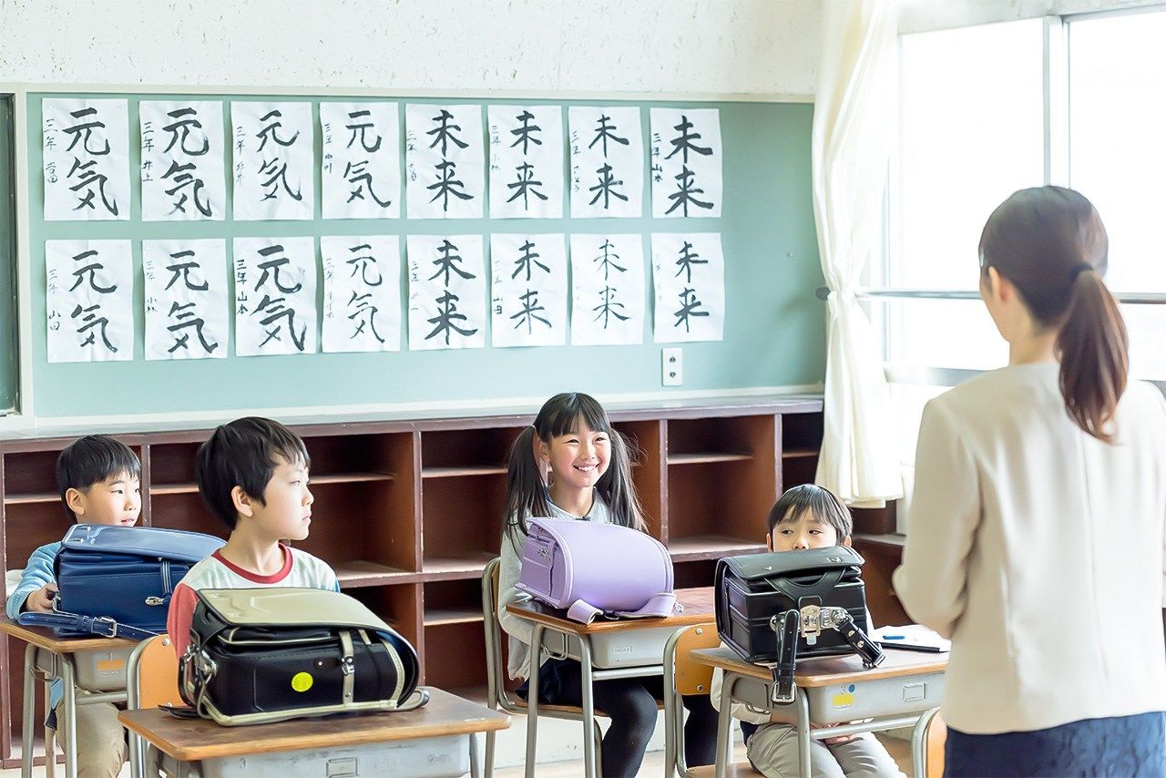 Les élèves prêts à rentrer chez eux, leur sac à dos, sur le bureau. Les idéogrammes 元気 et 未来 inscrits au fond signifient respectivement « en forme » (genki) et « avenir » (mirai). (Pixta)