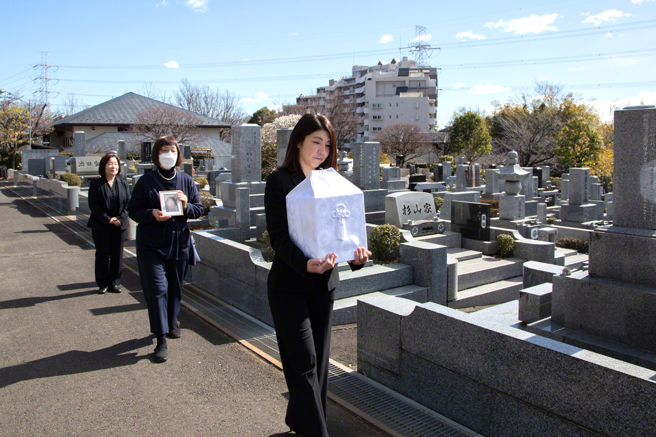 Un membre du personnel du Ending Center porte pr&eacute;cautionneusement une urne fun&eacute;raire avant inhumation.