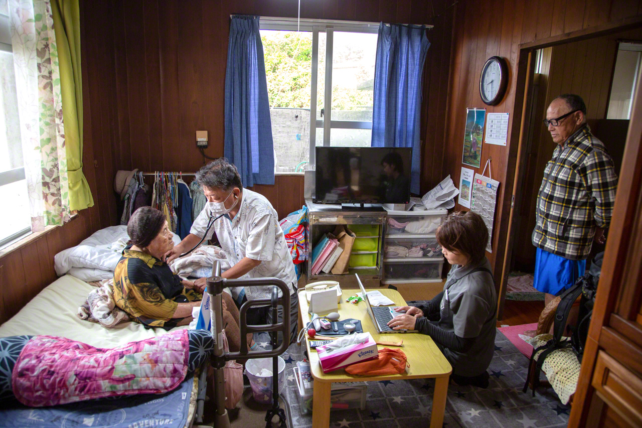Yasukawa Keigo ausculte Isa Tsuru (&acirc;g&eacute;e de 95 ans). Une ou deux fois par mois, un m&eacute;decin de la Clinique du Docteur Gon lui rend visite. Son fils, Teruo (&agrave; droite) observe, inquiet.